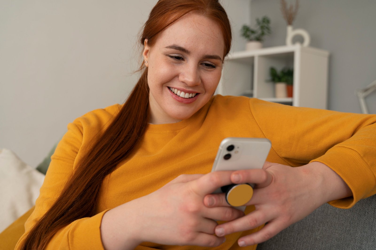 Castleblayney portrait woman using her smartphone home couch by holding from pop socket