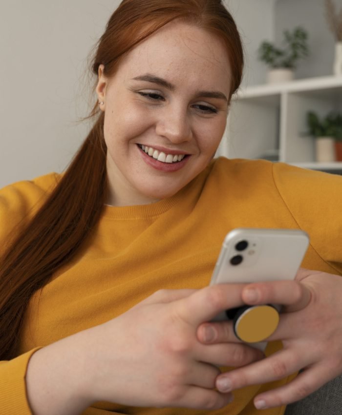 portrait woman using her smartphone home couch by holding from pop socket
